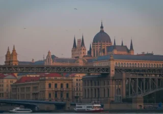 Scenic night view of Budapest’s Parliament Building lit up along the Danube River with Chain Bridge glowing under the evening sky.