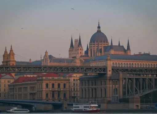 Scenic night view of Budapest’s Parliament Building lit up along the Danube River with Chain Bridge glowing under the evening sky.