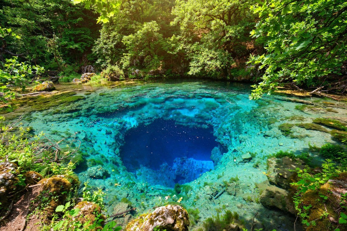 The vivid blue waters of the Blue Eye spring surrounded by green forest in southern Albania