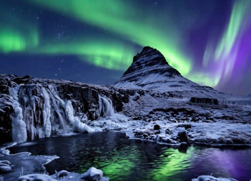 Northern lights dancing over a snow-covered Icelandic mountain and frozen waterfall at night