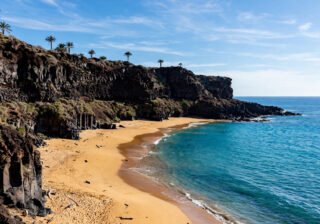 Sunny Canary Islands coastline with volcanic cliffs and golden beach in January