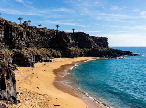 Sunny Canary Islands coastline with volcanic cliffs and golden beach in January