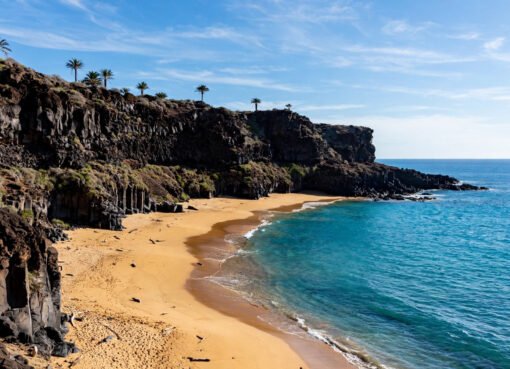 Sunny Canary Islands coastline with volcanic cliffs and golden beach in January