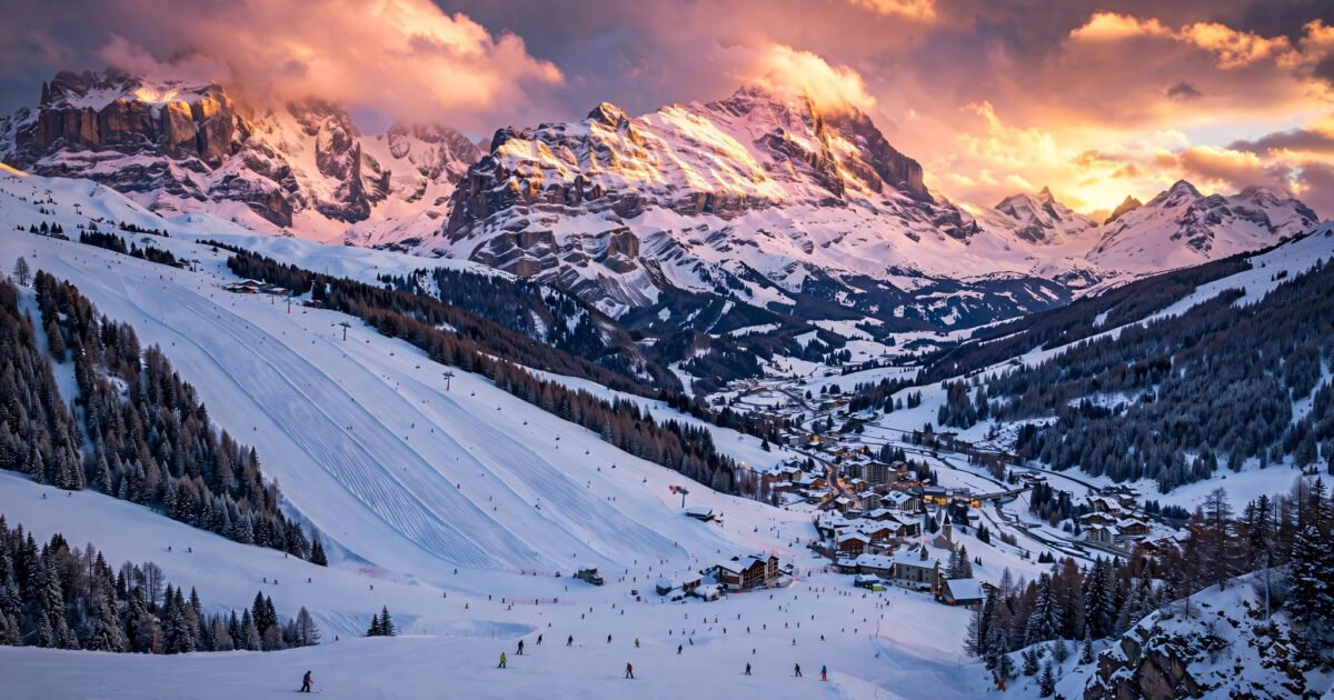 Panoramic golden-hour view of an affordable European ski resort with skiers on snowy slopes
