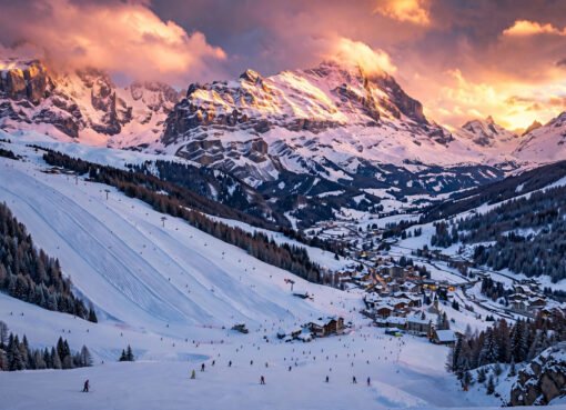 Panoramic golden-hour view of an affordable European ski resort with skiers on snowy slopes