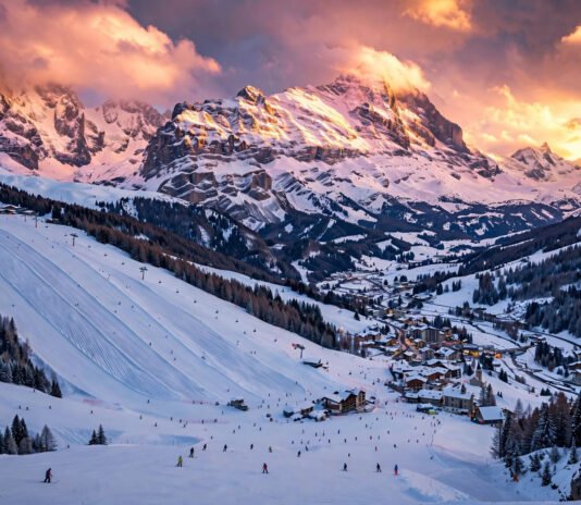 Panoramic golden-hour view of an affordable European ski resort with skiers on snowy slopes